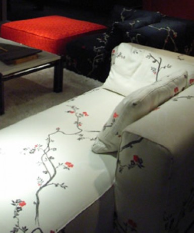 日本画のように繊細且つ大胆な描写で描かれた紅梅が映えるモダンな白いソファ